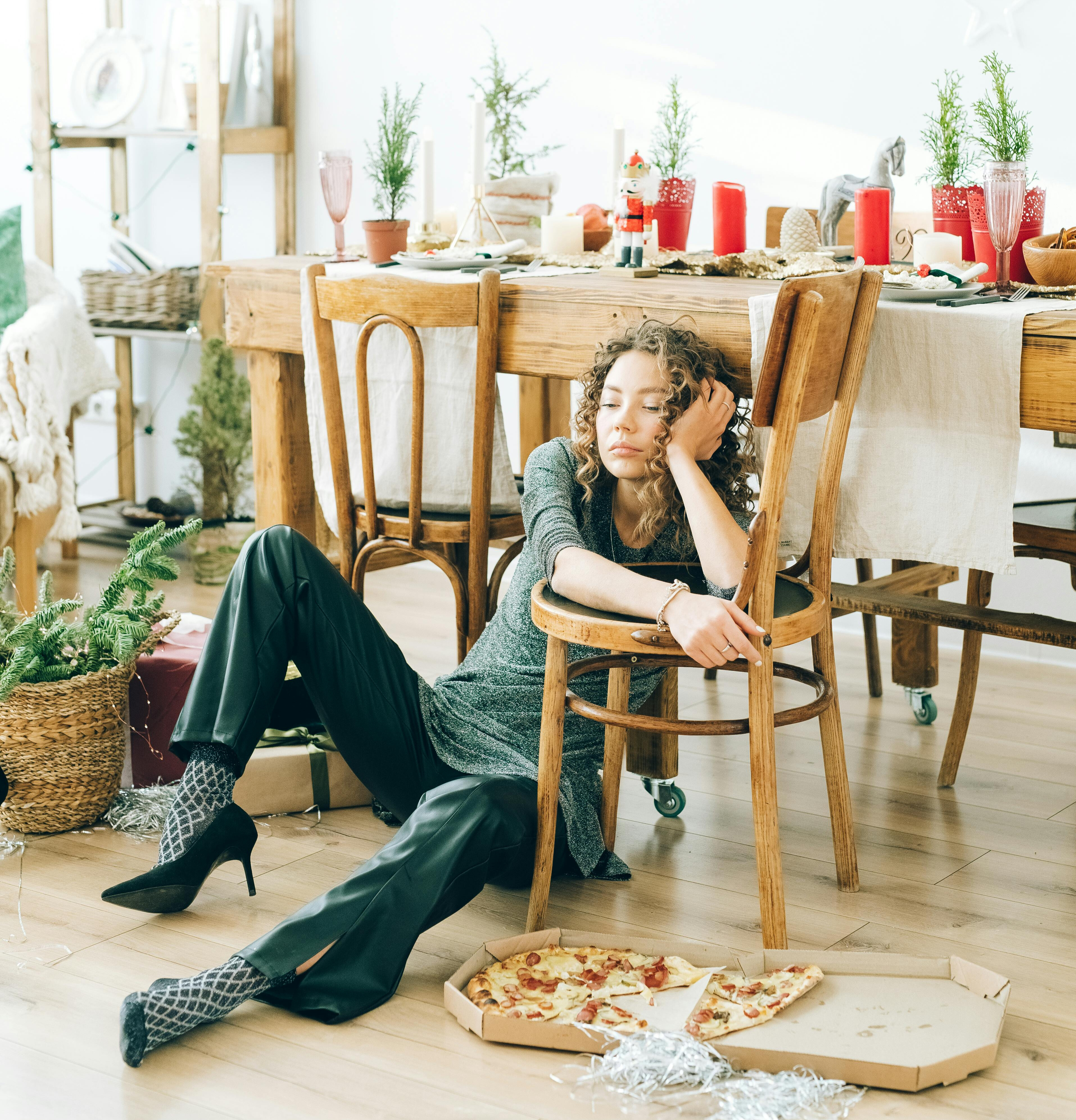 Woman sitting on the floor looking exhausted, pizza box beside her