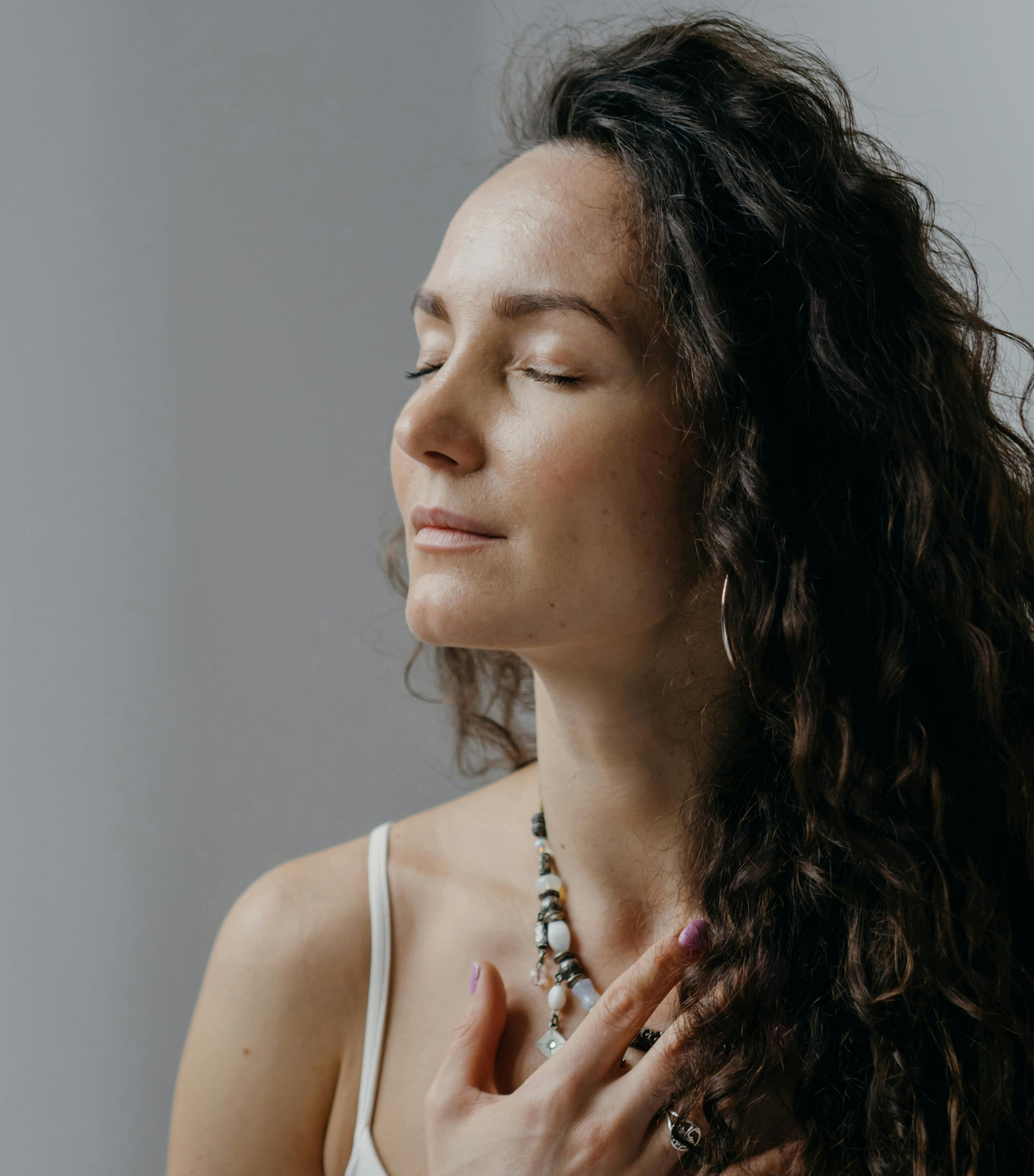 Woman with eyes closed, hand on chest, in a calm and grounded state